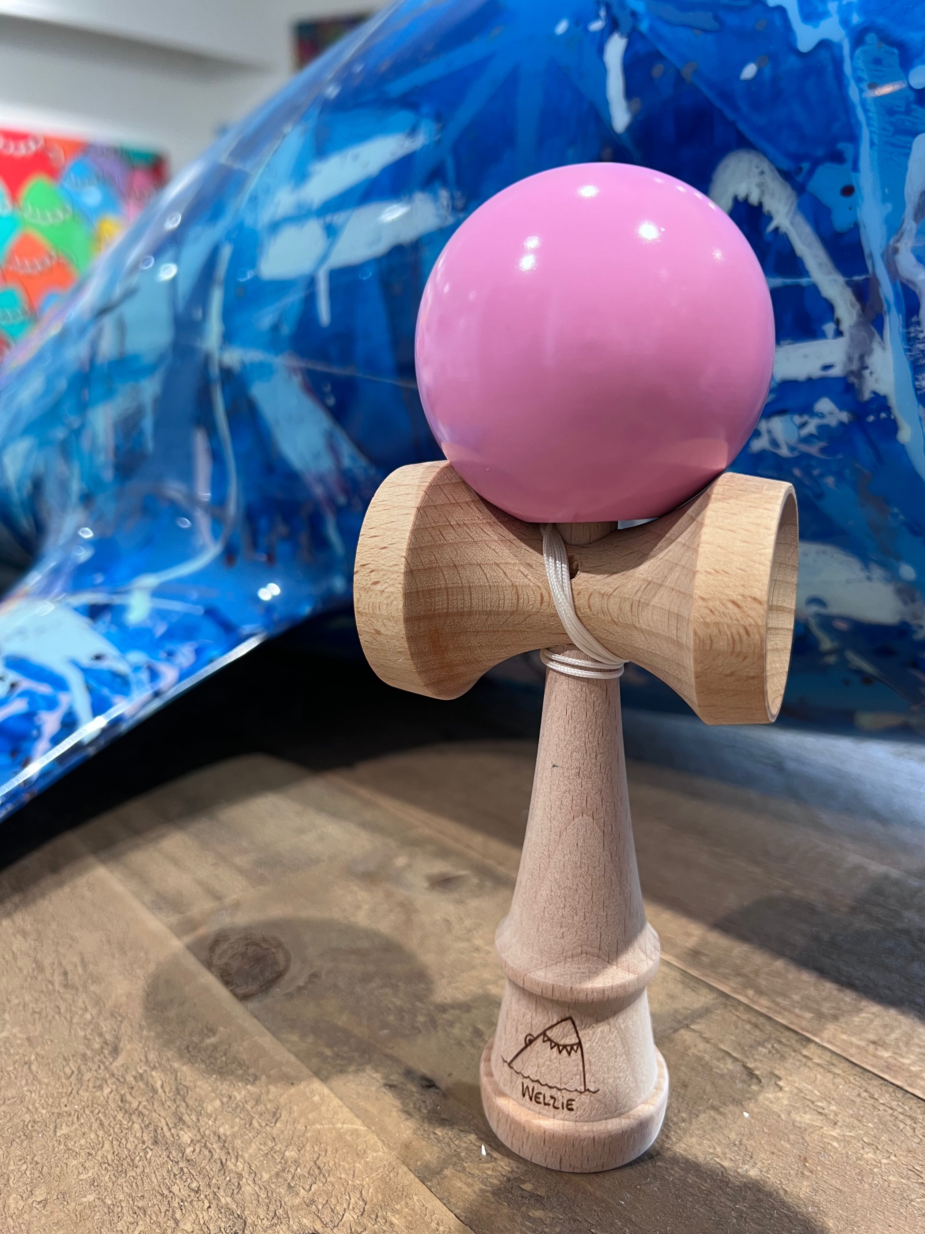 A close-up of several wooden kendama with a pink head.