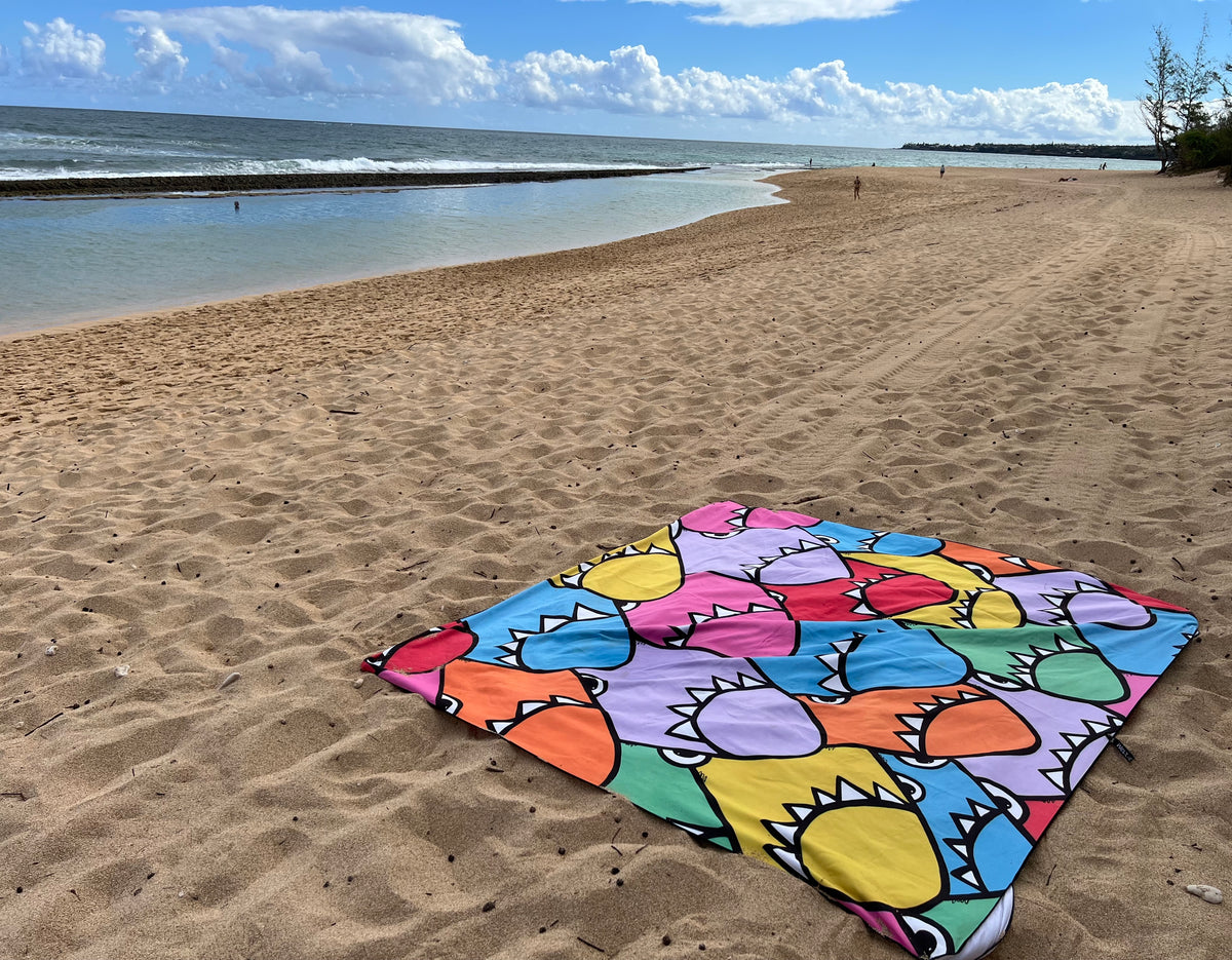Colorful beach towel on a sandy beach with ocean and sky in the background